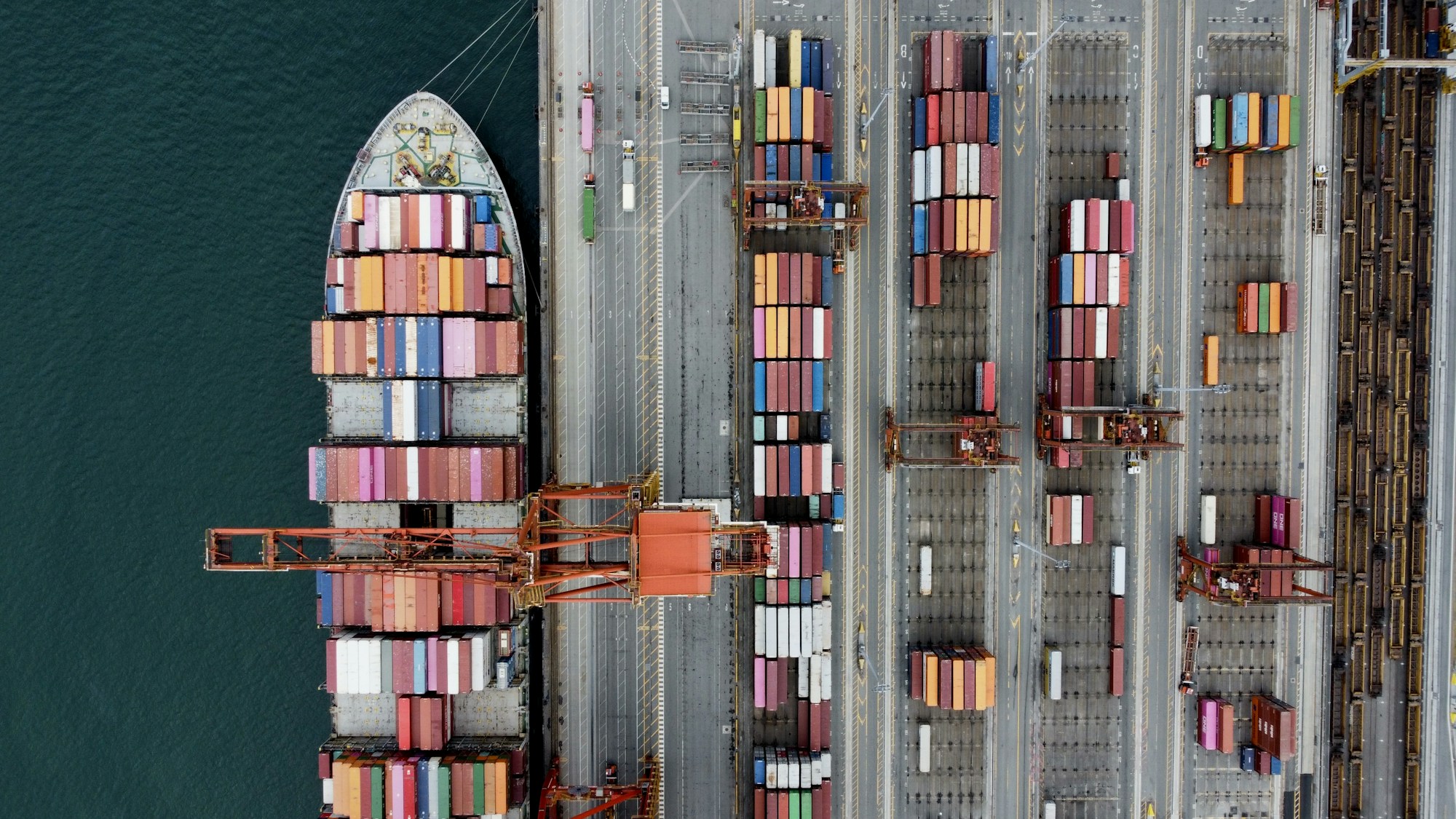 An aerial view of a container ship alongside a busy cargo terminal